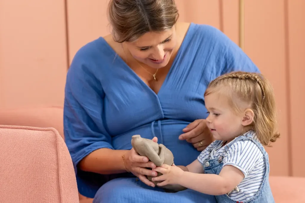 Wat is een zwangerschapsbeeldje? 2 Close-up van handen op een zwangere buik in zacht licht, passend bij een tastbare herinnering.